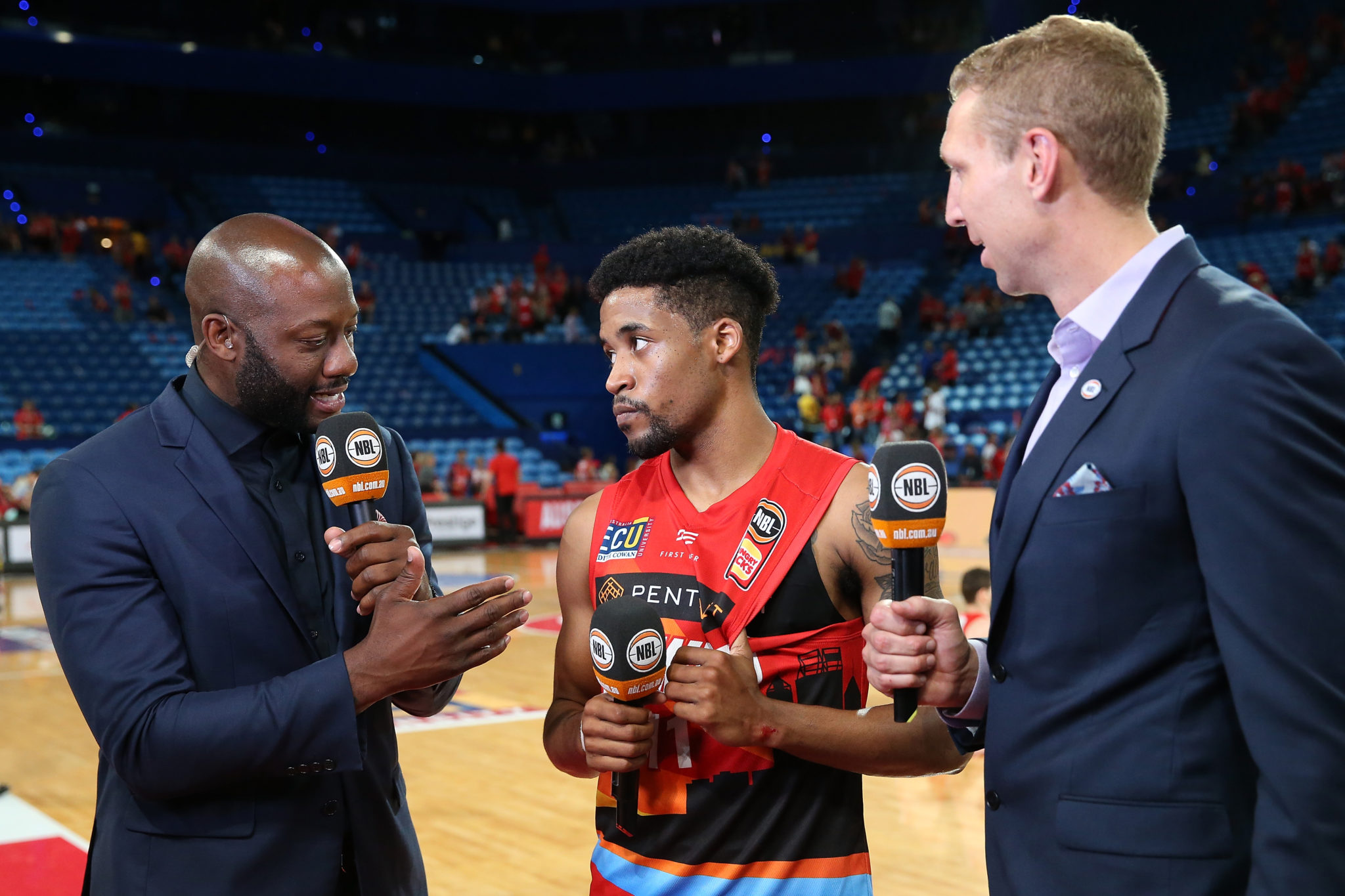 PERTH, AUSTRALIA - JANUARY 25: Bryce Cotton of the Wildcats talks with NBL commentators Corey Williams and Shawn Redhage after winning the round 15 NBL match between the Perth Wildcats and the Adelaide 36ers at Perth Arena on January 25, 2019 in Perth, Australia. (Photo by Paul Kane/Getty Images)